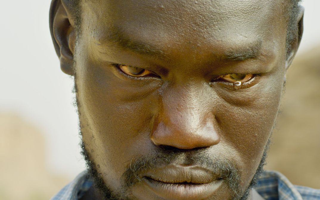 Film still from THE DAM: Close-up of a man with a tear in the corner of his eye.