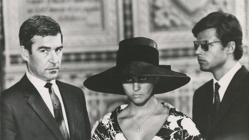Film still from VAGHE STELLE DELL'ORSA: Three people can be seen, the woman in the middle is wearing a large hat.