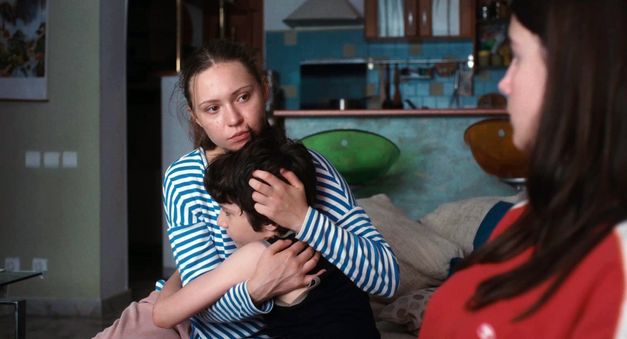 Junge Frau hält ein Kind im Arm, eine weitere Frau sitzt ihr gegenüber.