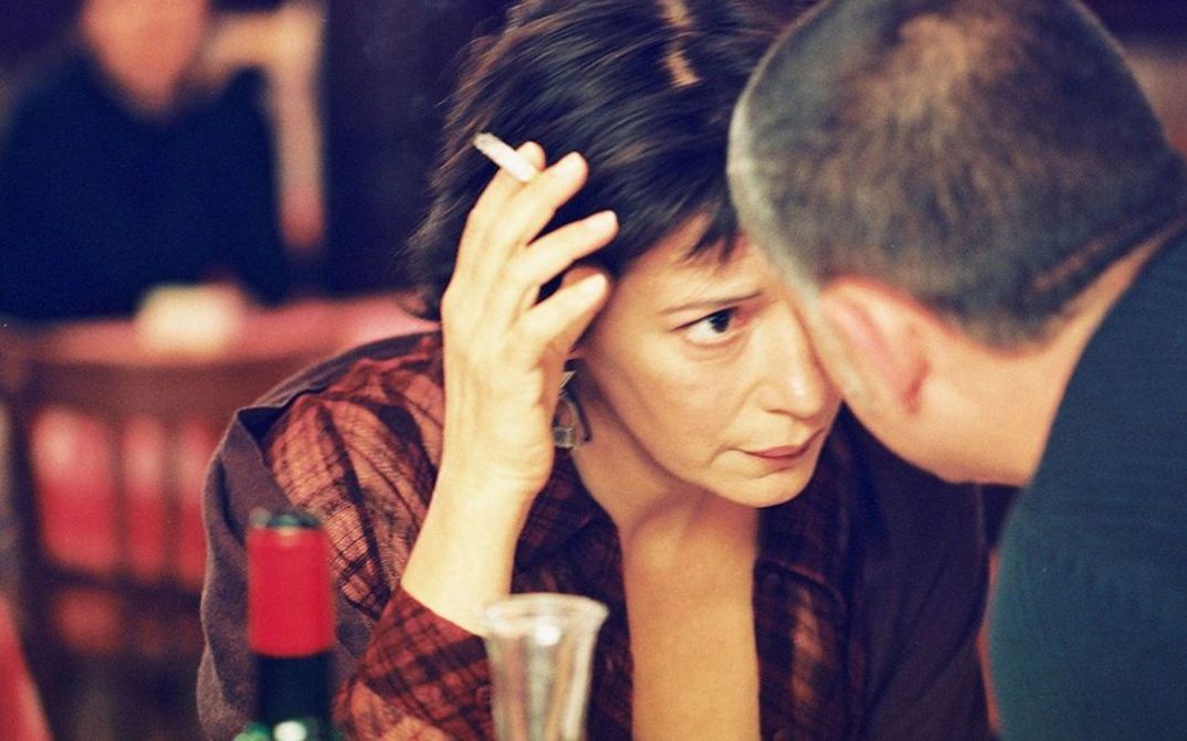Filmstill aus LA CHOSE PUBLIQUE. Eine Frau und ein Mann in einem Restaurant stecken die Köpfe zusammen.