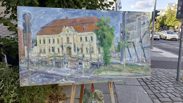 Film still from 2024 (2023) by Stefan Hayn. The image shows a painting of a Jewish memorial on an easle outside.