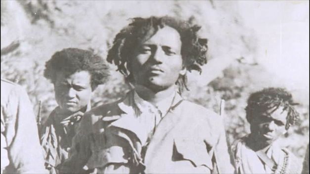 Historische Schwarzweißaufnahme von drei Personen in Uniform, die nebeneinander stehen und in die Kamera blicken.