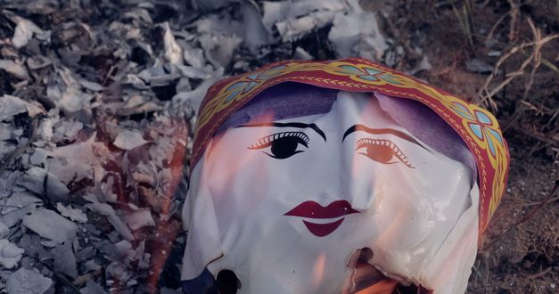 Filmstill aus „Memoryland“ von Kim Quy Bui. Ein aufgeblasener Plastikballon mit einem Gesicht drauf geht in Flammen auf.