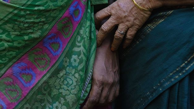 Detailaufnahme von Händen auf farbigem Stoff, ruhige Geste.