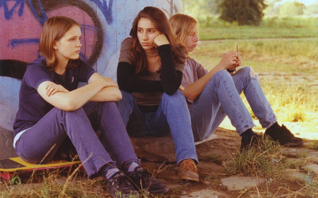 Film still from MACH DIE MUSIK LEISER: Three teenagers sit bored in front of a bridge pillar.