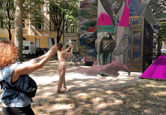 Still from “Alternative Monument for Germany (AMfG)” by Alternative Monument. Through their smartphones, two people explore the augmented reality installation. They stand before one of the monument