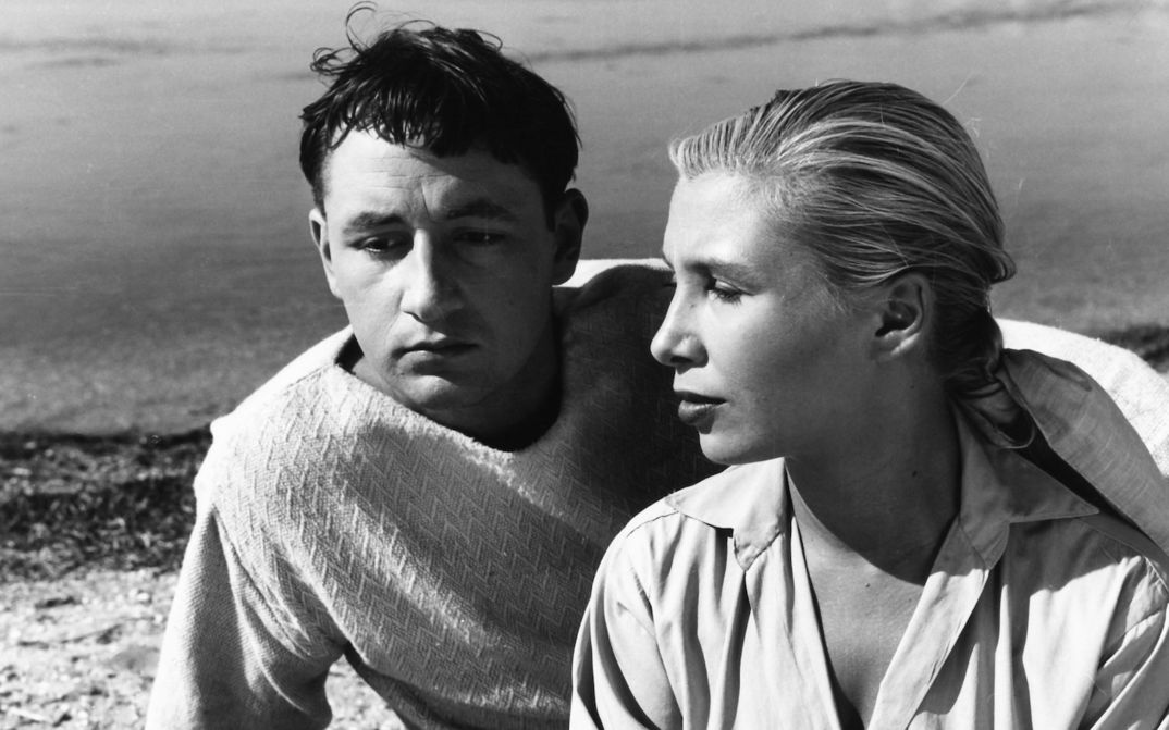 Filmstill aus LA POINTE COURTE: Ein junges Paar sitzt an am Meer und blickt träumerisch in die Ferne.