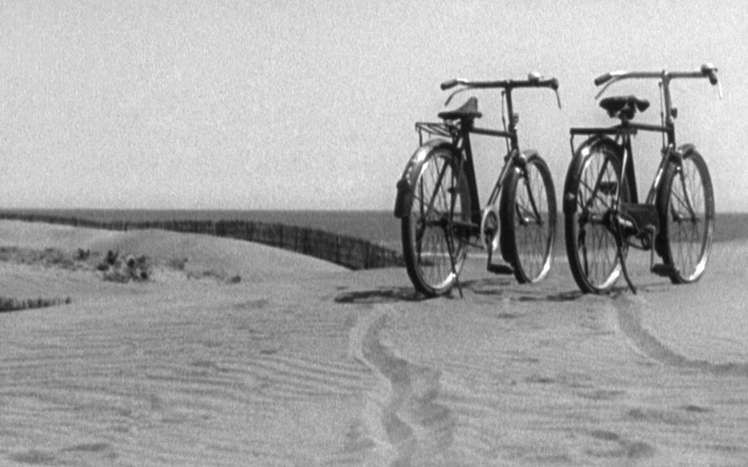 Film still from BANSHUN: Two bicycles are standing next to each other on a sand dune.