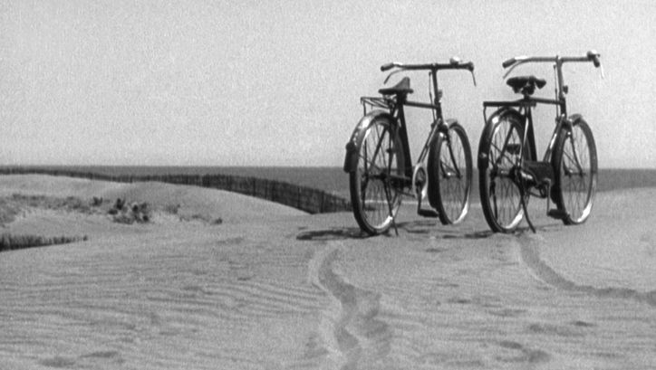 Film still from BANSHUN: Two bicycles are standing next to each other on a sand dune.