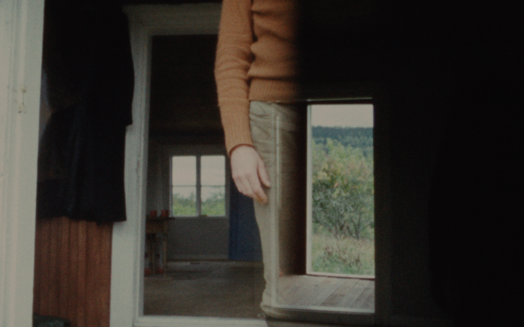 Filmstill aus KASKARA: Man sieht übereinandergelegte Bilder; das Innere eines Hauses, den Körper einer Person ohne den Kopf.