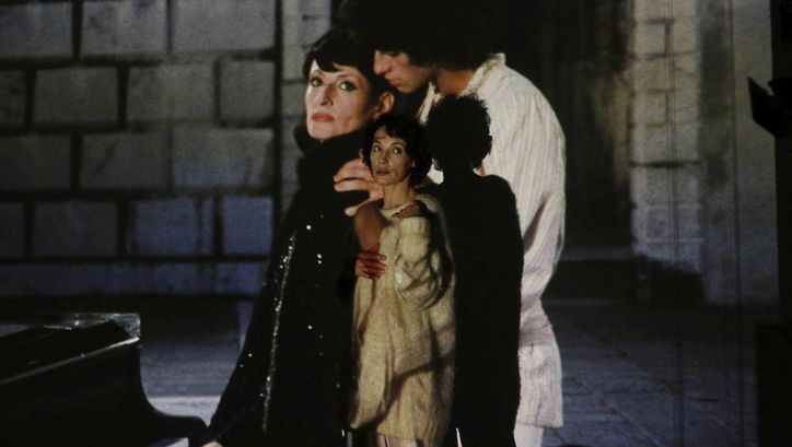 Filmstill aus BARBARA. Eine Frau steht vor einer Leinwand, auf die ein Mann und eine Frau projiziert sind.