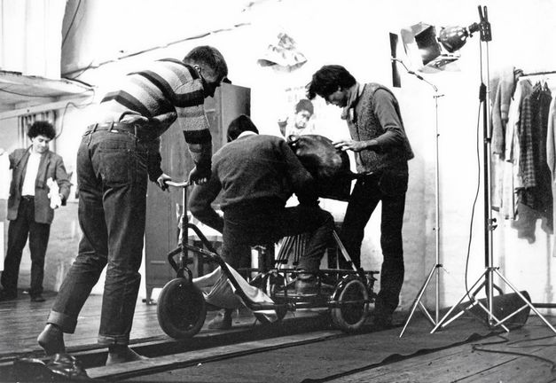 Foto von den Dreharbeiten zu „In der Wüste“ von Rafael Fuster Pardo. Ein Schwarzweiß-Bild von drei Männern auf einem Kamerawagen auf Schienen. 