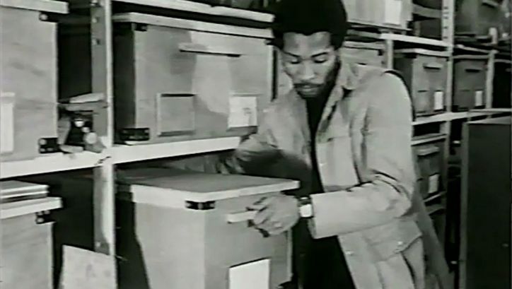 Filmstill aus YOU HIDE ME: Ein Mann zieht eine große Schachtel aus einem Regal.