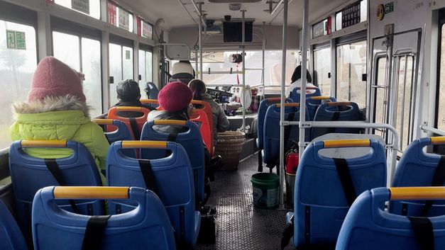 Film still from the movie FRUIT FARM by Nana Xu. The picture shows some passengers from the back of a bus.