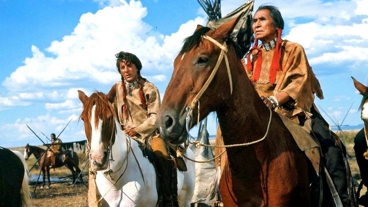 Filmstill aus LITTLE BIG MAN: Zwei Männer in indianischer Kleidung sitzen auf Pferden.