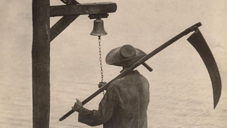Filmstill aus VAMPYR: Man sieht von hinten einen Mann mit Hut und einer Sense, der an Glocke klingelt.