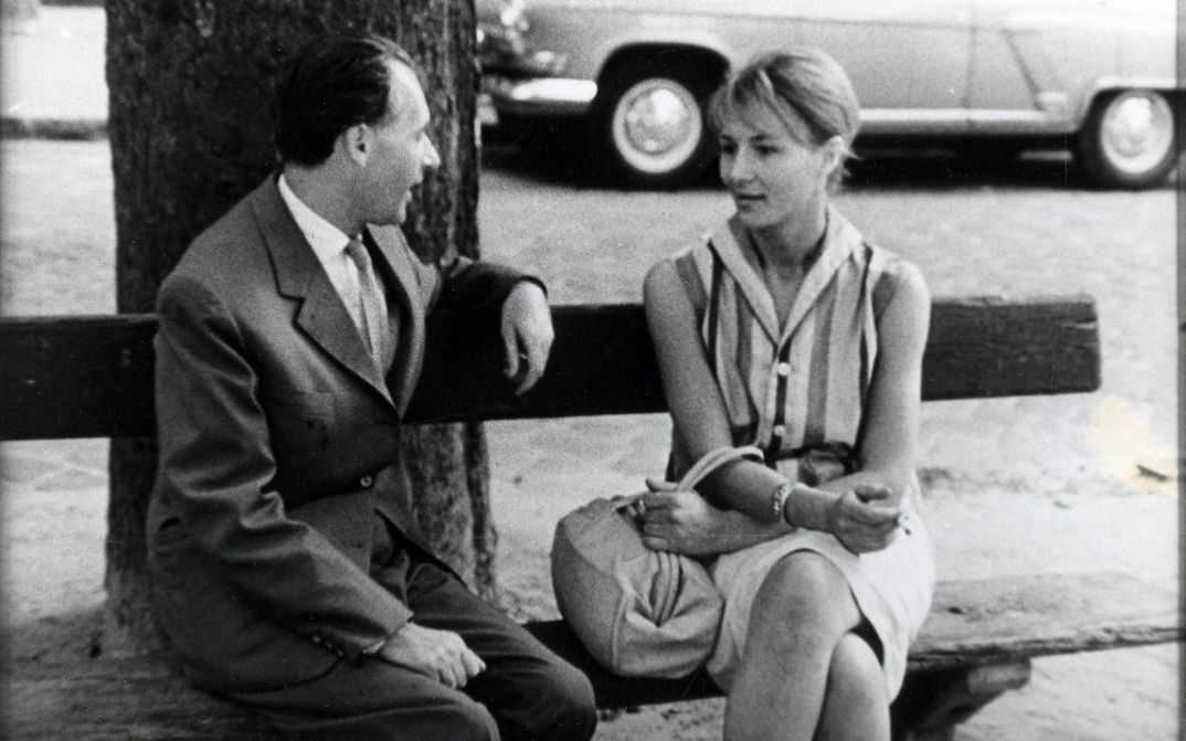 Eine Mann und eine Frau sitzen auf einer Parkbank und sprechen miteinander.