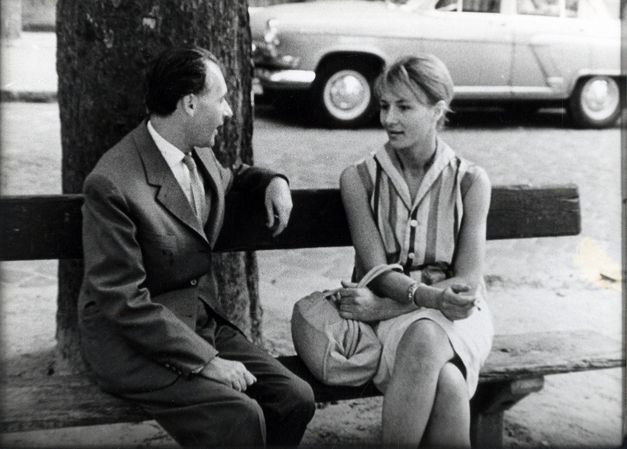 Eine Mann und eine Frau sitzen auf einer Parkbank und sprechen miteinander.