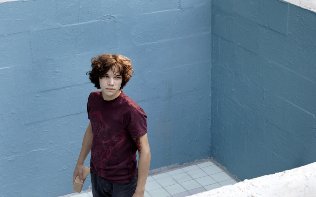 Film still from PINGPONG: A teenager stands in an empty pool.