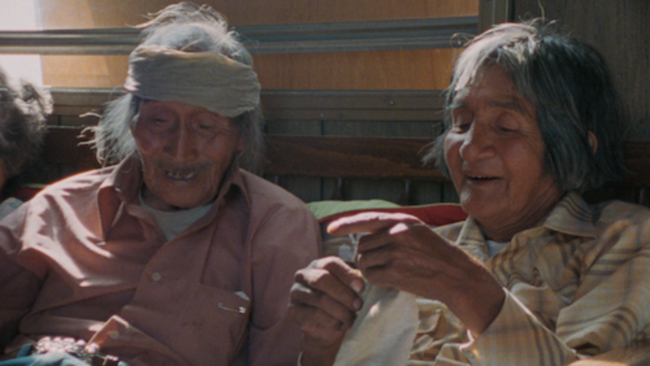 Film still from Techqua Ikachi – Land, mein Leben:  It shows an old man and an old woman sitting next to each other.