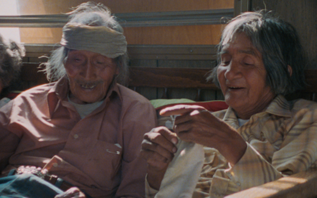 Filmstill aus Techqua Ikachi – Land, mein Leben: Zu sehen sind ein alter Mann und eine alte Frau, die nebeneinander sitzen.