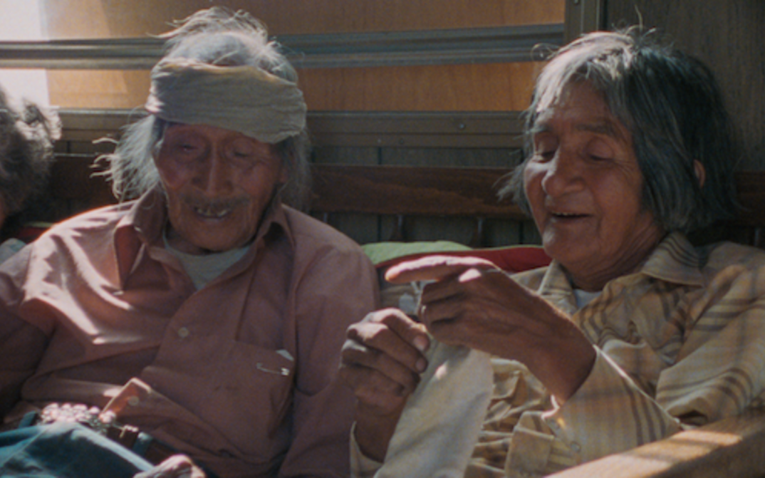 Film still from Techqua Ikachi – Land, mein Leben:  It shows an old man and an old woman sitting next to each other.