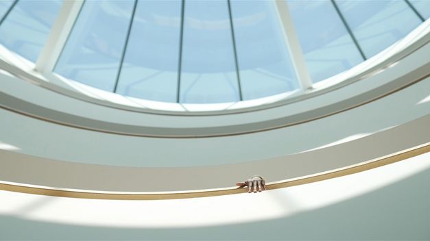 Still from the Film "Jail Bird in a Peacock Chair" by James Gregory Atkinson. A glass dome and a hand reaching over a railing.