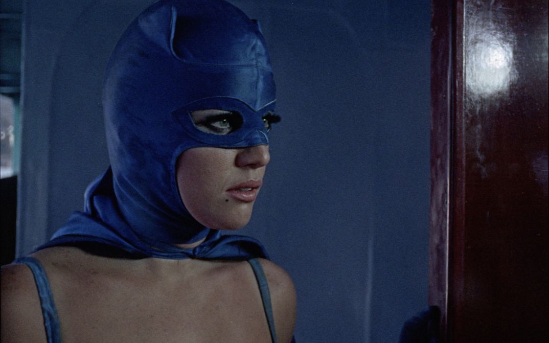 Filmstill aus LA MUJER MURCIÉLAGO: Großaufnahme einer Frau im lila Superheldinnen-Kostüm.