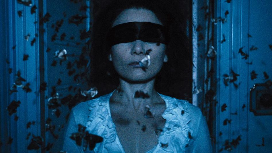 Filmstill aus THE DUKE OF BURGUNDY: Eine Frau mit verbundenen Augen, umschwirrt von Schmetterlingen.
