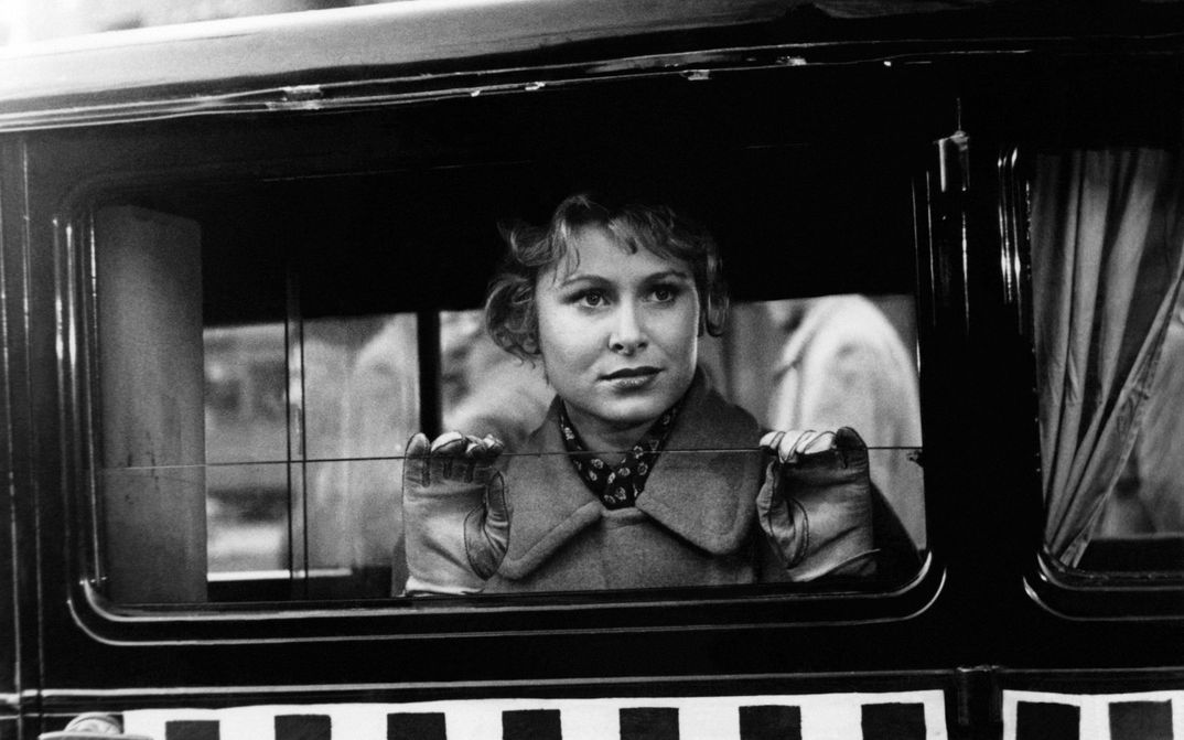 Film still from LISSY: A young woman looks out of a car or bus and holds her hands against the lowered window.
