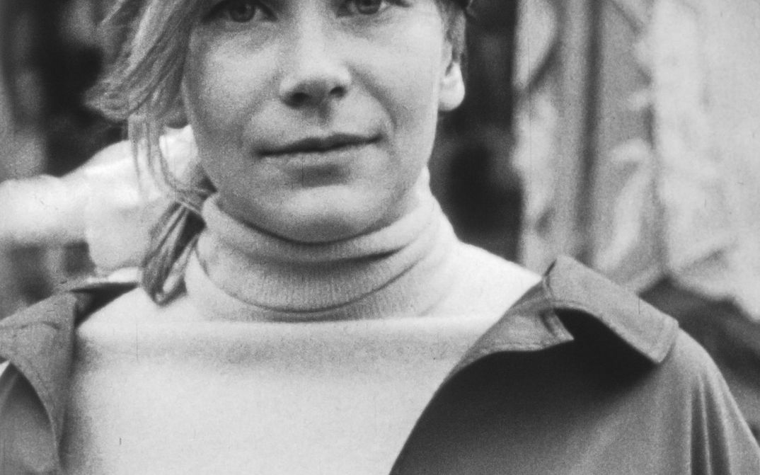 Filmstill aus SUBJEKTITÜDE. Großaufnahme einer jungen Frau, die frontal in die Kamera blickt.