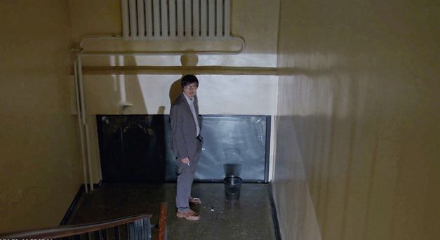 Filmstill aus „Akyn (Poet)“ von Darezhan Omirbayev. Ein Mann raucht alleine in einem Treppenhaus. 