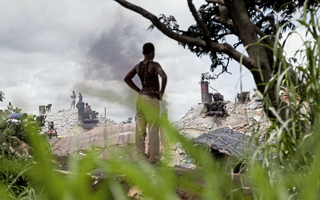 Filmstill aus „Or de vie“ von Boubacar Sangaré. Zu sehen ist der oberirdische Teil eines Goldsucher-Bergwerks. Im Vordergrund steht der 16-jährige Rasmané mit dem Rücken zur Kamera.