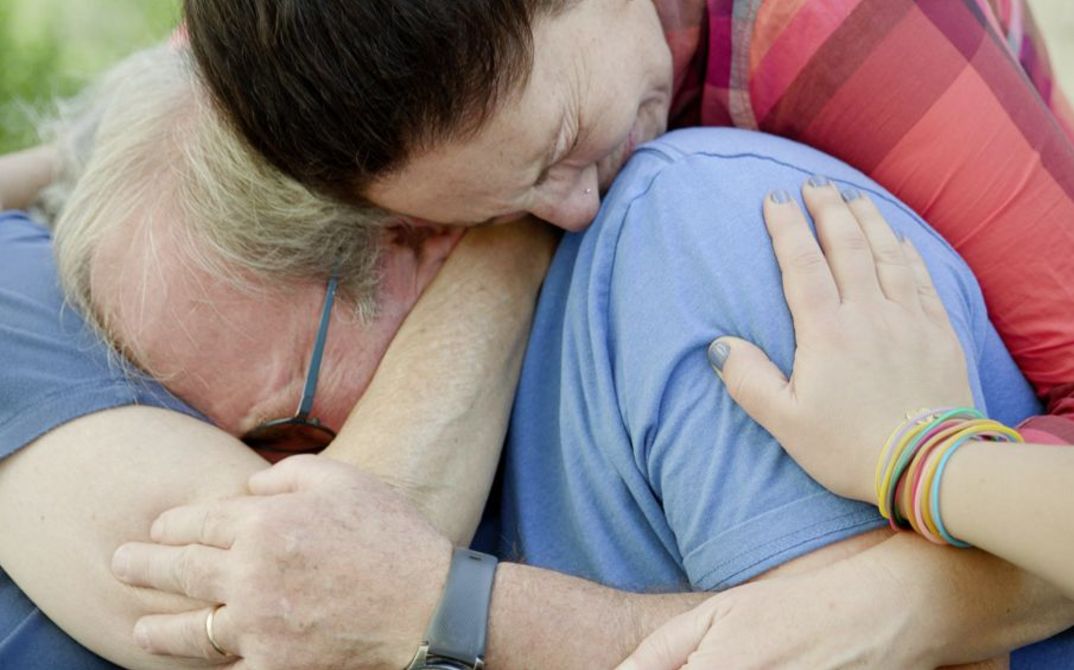 Film still from HOLDING LIAT by Brandon Kramer. The picture shows three crying people hugging each other.