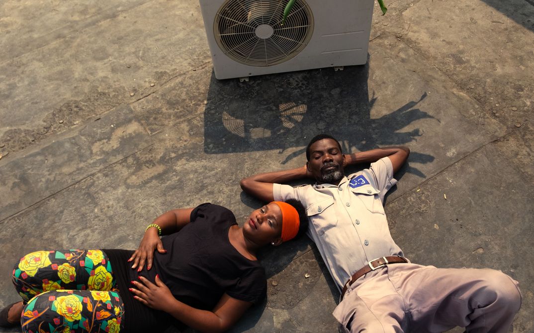 Filmstill aus AIR CONDITIONER: Ein Mann und eine Frau liegen nebeneinander auf dem Boden, neben ihnen steht ein Ventilator.