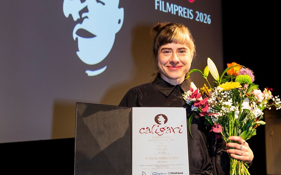 The director with two toned hair with a certificate and a boquet of flowers in her hand. 