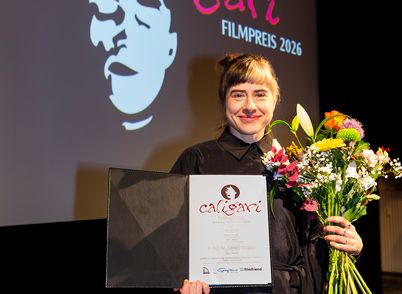 The director with two toned hair with a certificate and a boquet of flowers in her hand. 