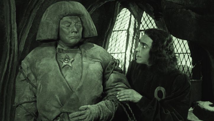 Filmstill aus DER GOLEM, WIE ER IN DIE WELT KAM: Ein Mann blickt erschrocken auf die Lehmfigur des Golem.
