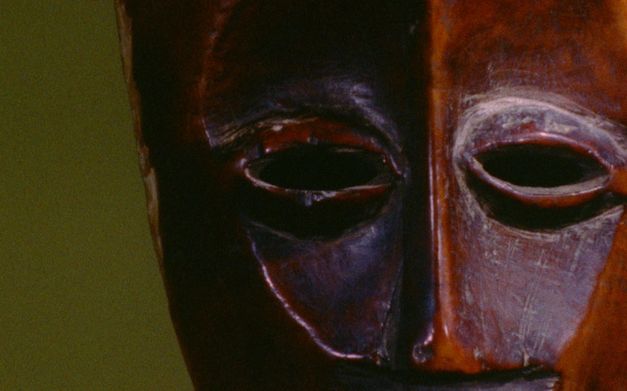 Filmstill aus dem Film "Under the White Mask: The Film That Haesaerts Could Have Made" von Matthias De Groof. Man sieht eine Holzmaske vor einem grünen Hintergrund.