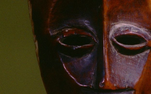 Still from the film "Under the White Mask: The Film That Haesaerts Could Have Made" by Matthias De Groof. A wooden mask against a green background.