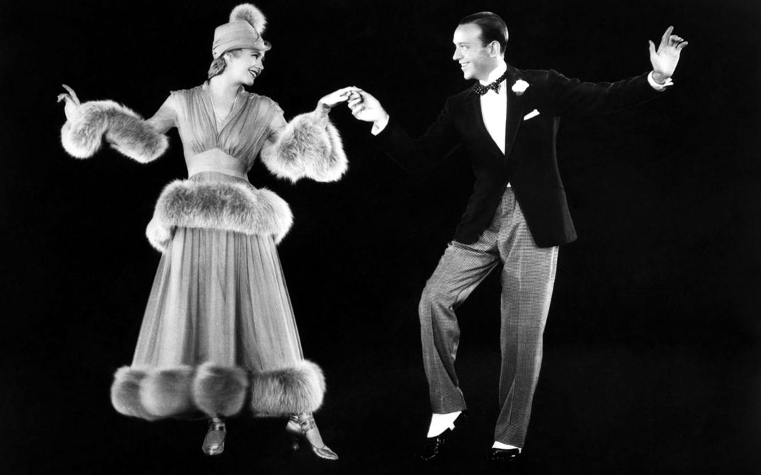 Film still from THE STORY OF VERNON AND IRENE CASTLE. Ginger Rogers and Fred Astaire dance against a black background.