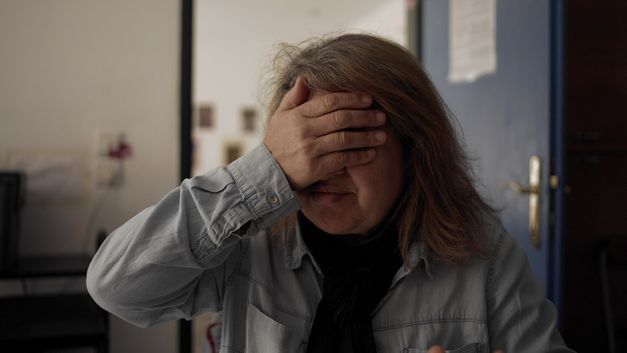 A woman covers her eyes with her right hand. 
