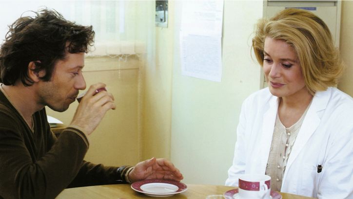 Filmstill aus ROIS ET REINE. Mathieu Amalric und Catherine Deneuve an einem Tisch, vor sich Kaffeetassen.