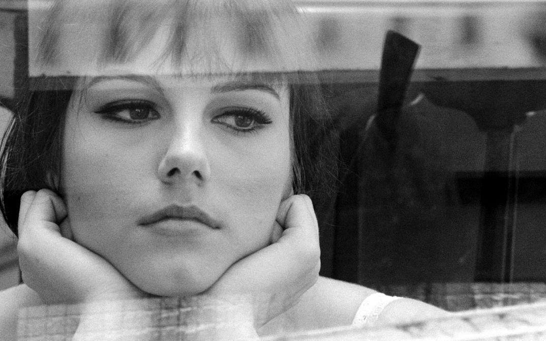 Filmstill aus IO LA CONOSCEVO BENE: Eine junge Frau blickt nachdenklich aus dem Fenster, das Gesicht in die Hände gestützt.