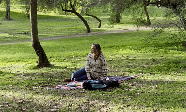 Filmstill from "Cidade Rabat" by Susana Nobre. A woman sits on a blanket in a clearing.