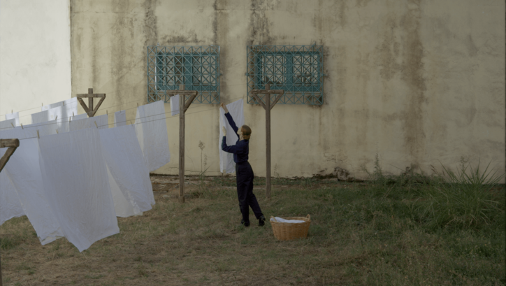 Film still from MUSIC: A woman hangs laundry outdoors.