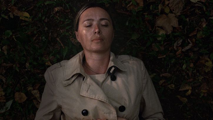 Filmstill aus BEGINNING. Eine Frau liegt mit geschlossenen Augen im Gras.
