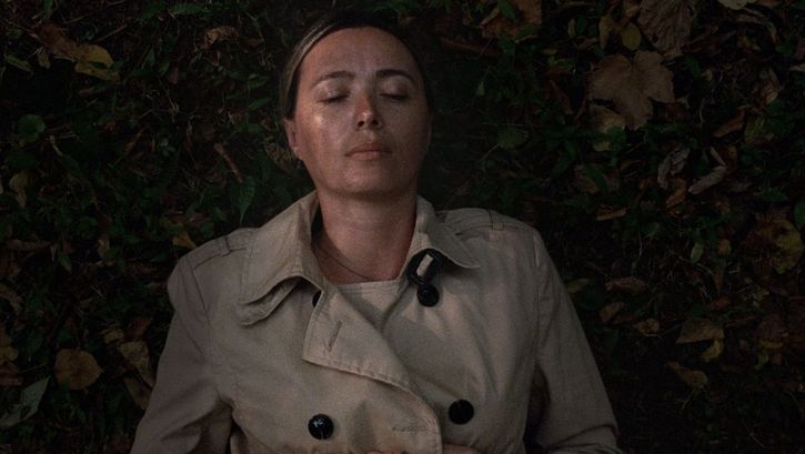 Filmstill aus BEGINNING. Eine Frau liegt mit geschlossenen Augen im Gras.