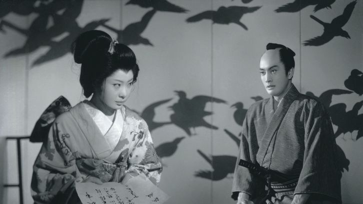 Film still from SWORD OF DOOM: A man and a woman in traditional Japanese kimonos are sitting in a room. The wall behind them is painted with birds.