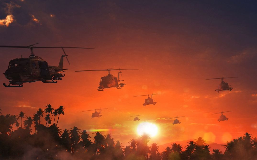 Film still from APOCALYPSE NOW: Several helicopters fly over palm trees in an orange sky.